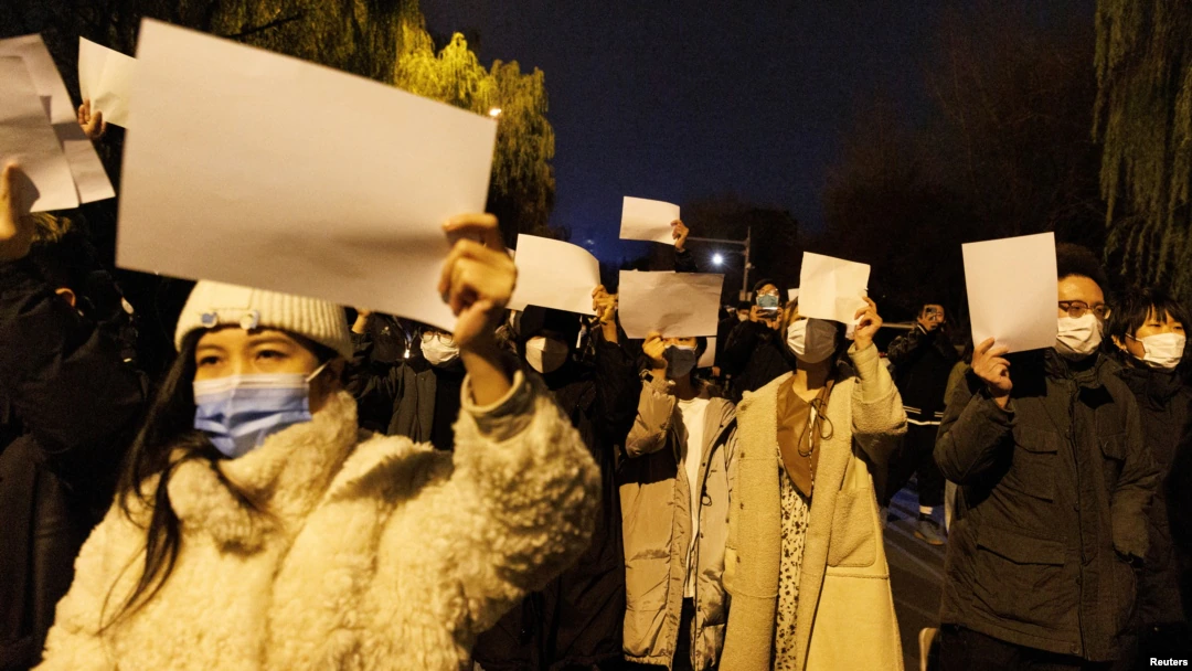 北京民众手举白纸上街游行，抗议中国的清零防疫政策，悼念乌鲁木齐火灾死难者。（2022年11月27日）/ 路透社